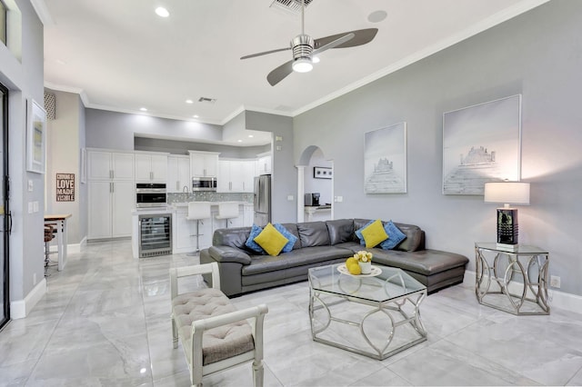 living area featuring beverage cooler, ceiling fan, marble finish floor, and arched walkways