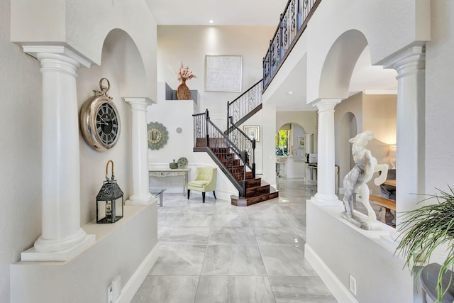 entryway with stairs, a high ceiling, and marble finish floor