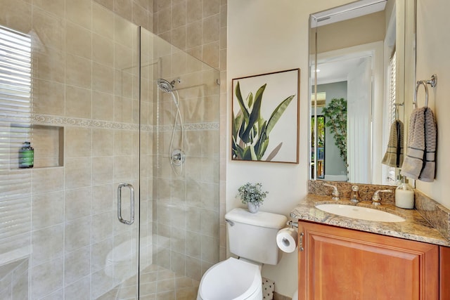 bathroom with a stall shower, toilet, and vanity