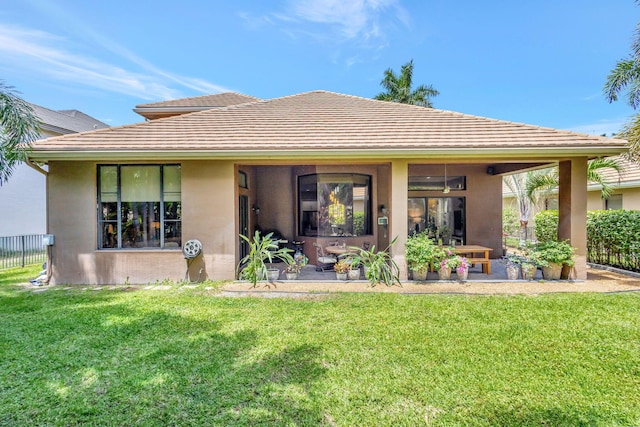 rear view of house featuring a patio, fence, stucco siding, and a yard