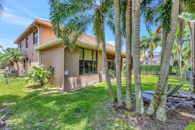 view of property exterior with fence private yard, stucco siding, and a yard