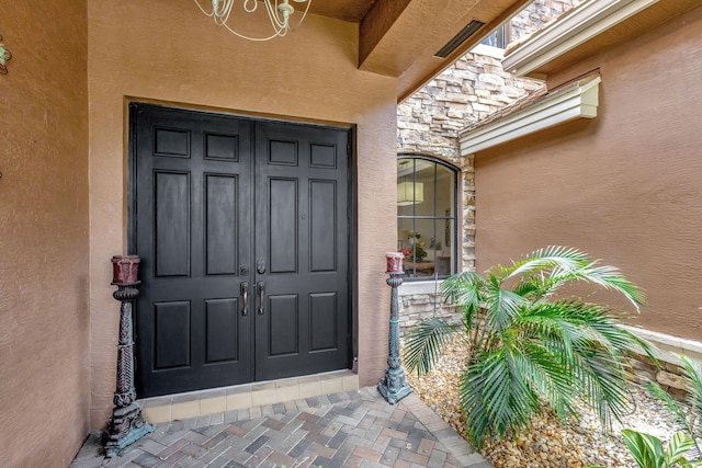 view of exterior entry featuring stucco siding and stone siding