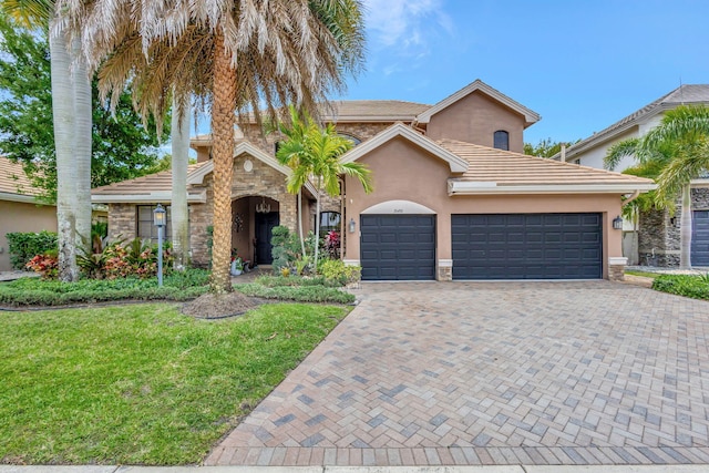 mediterranean / spanish house with a front lawn, stucco siding, decorative driveway, and stone siding