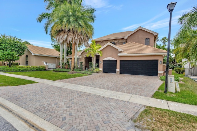 mediterranean / spanish-style house featuring stucco siding, a front yard, and a garage