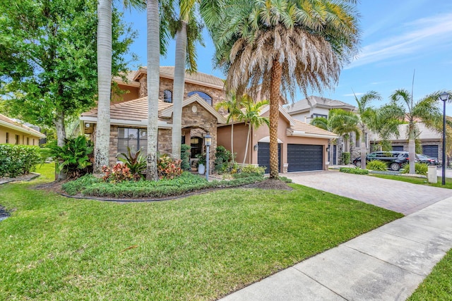 view of front of property featuring driveway, a tile roof, stone siding, a front yard, and stucco siding