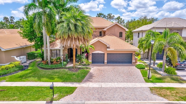 view of front of home featuring a tiled roof, decorative driveway, an attached garage, stucco siding, and a front lawn