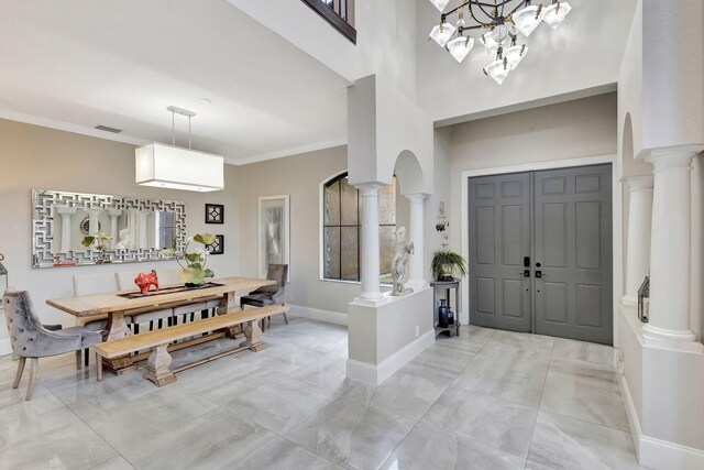 entrance foyer featuring ornate columns, visible vents, baseboards, ornamental molding, and arched walkways