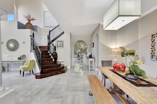 entryway featuring stairway, a towering ceiling, and arched walkways
