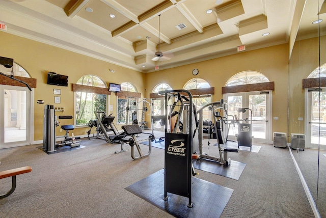 exercise room featuring coffered ceiling, a wealth of natural light, ceiling fan, crown molding, and a towering ceiling
