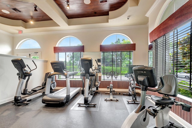 exercise room with visible vents, a tray ceiling, baseboards, wooden ceiling, and ornamental molding
