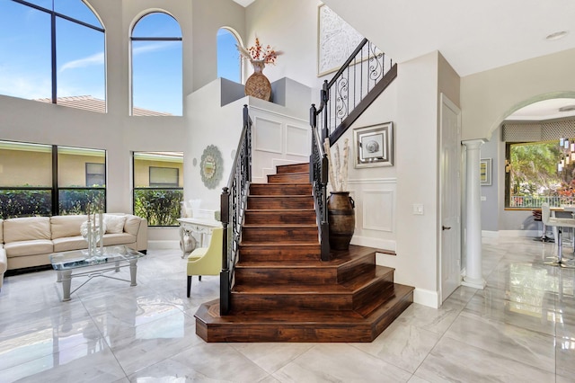 stairs with ornate columns, arched walkways, a towering ceiling, and marble finish floor
