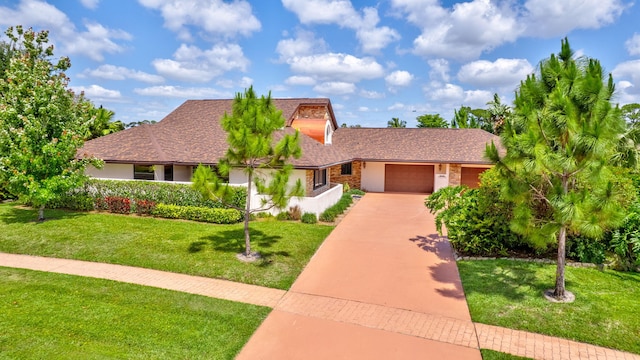 view of front of property with concrete driveway, a front lawn, and an attached garage