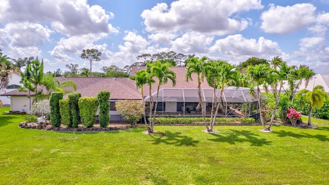 back of house featuring a lawn and a lanai