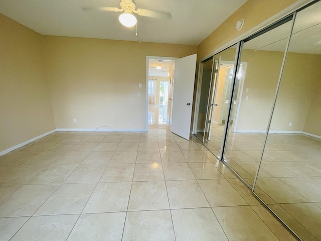 unfurnished bedroom featuring baseboards, ceiling fan, and a closet