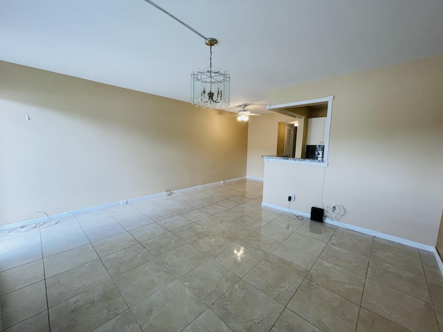 spare room featuring baseboards and ceiling fan with notable chandelier