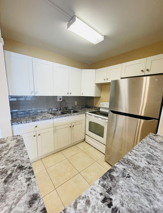 kitchen featuring a sink, light tile patterned floors, white cabinetry, freestanding refrigerator, and electric range