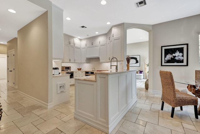2465 Chesapeake Cir, West Palm Beach, FL 33409 - kitchen with light countertops, arched walkways, recessed lighting, visible vents, and stone tile flooring