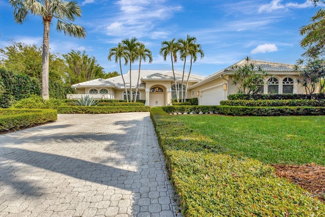 2465 Chesapeake Cir, West Palm Beach, FL 33409 - view of front of property with a front lawn, stucco siding, an attached garage, and a tiled roof