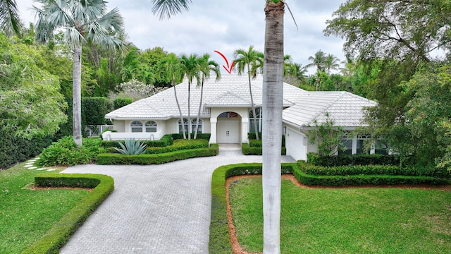 2465 Chesapeake Cir, West Palm Beach, FL 33409 - mediterranean / spanish house with a garage, stucco siding, a front yard, decorative driveway, and a tiled roof