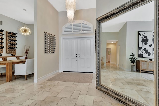 2465 Chesapeake Cir, West Palm Beach, FL 33409 - entryway featuring baseboards, a high ceiling, stone tile floors, and a chandelier