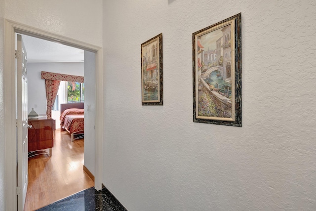 hall with a textured wall and wood finished floors
