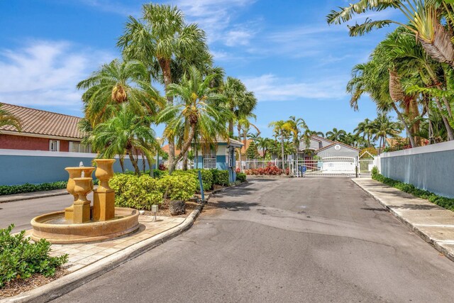 view of street with sidewalks, a gated entry, a gate, and curbs