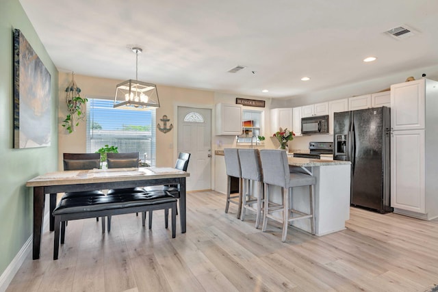 5810 Tucker Rd, Jupiter, FL 33458 - kitchen featuring black appliances, white cabinets, a kitchen breakfast bar, a chandelier, and light wood-style floors
