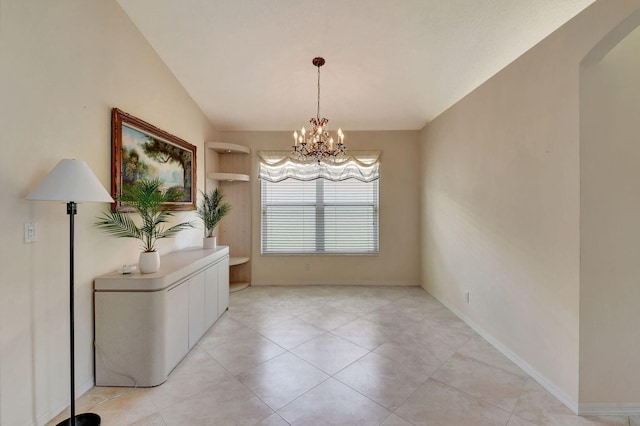 unfurnished dining area featuring arched walkways, baseboards, an inviting chandelier, and light tile patterned flooring