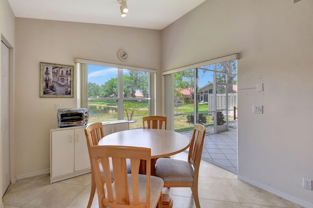 dining space with light tile patterned flooring, baseboards, a water view, and a toaster