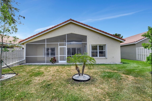 back of house featuring fence, a tile roof, stucco siding, a sunroom, and a yard