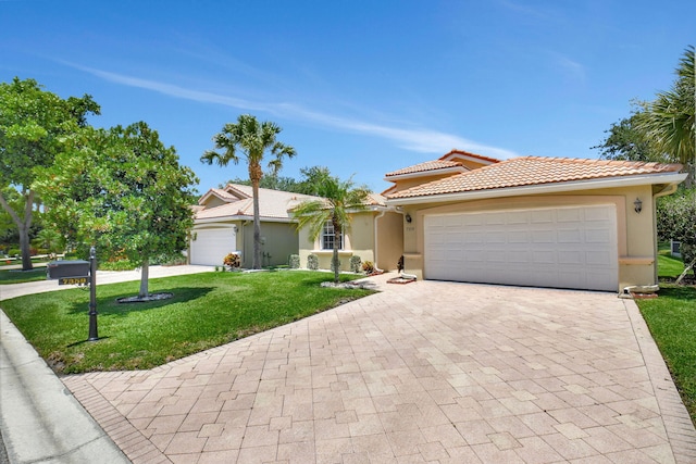 view of front of home with a tiled roof, driveway, a front lawn, an attached garage, and stucco siding