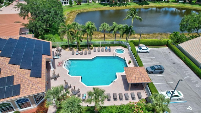 pool featuring a water view, a community hot tub, and a patio area
