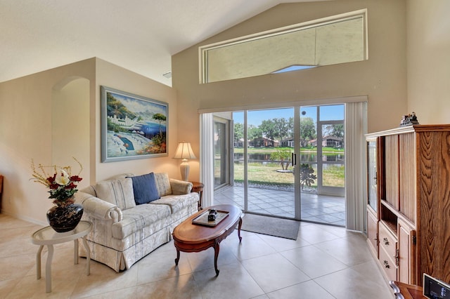 living area featuring light tile patterned flooring, high vaulted ceiling, and a water view
