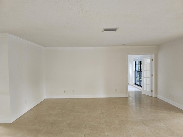 unfurnished room with a textured ceiling, visible vents, light tile patterned floors, and baseboards