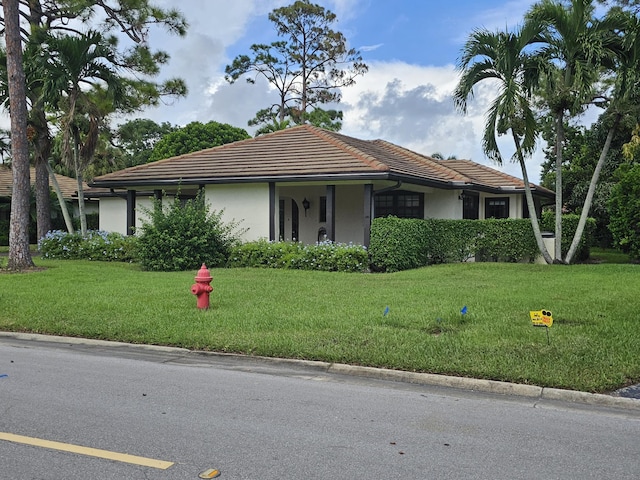 view of front of home with stucco siding, a front lawn, and a tile roof