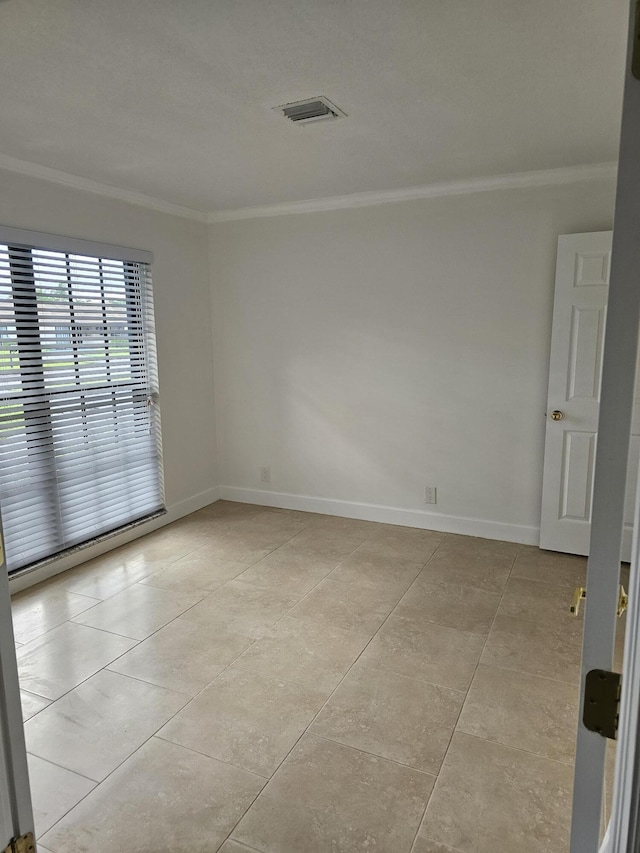 spare room with baseboards, visible vents, light tile patterned flooring, and crown molding