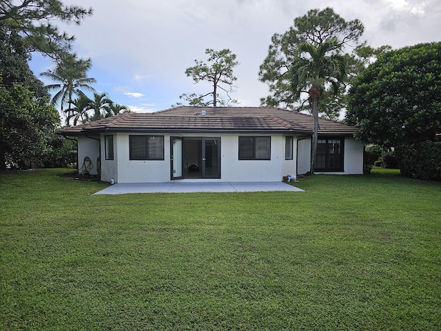 back of property featuring a tile roof, a lawn, stucco siding, and a patio area