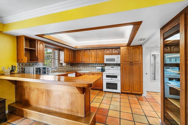 kitchen with white appliances, decorative backsplash, brown cabinetry, a sink, and a peninsula