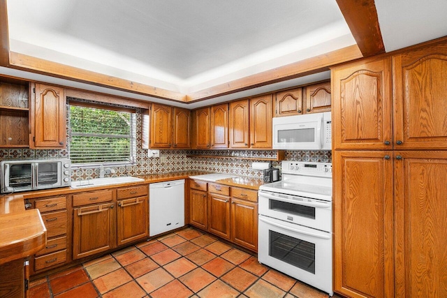 kitchen with a sink, a toaster, white appliances, brown cabinetry, and backsplash