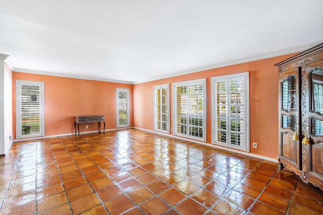 tiled empty room with ornamental molding, a wealth of natural light, and baseboards