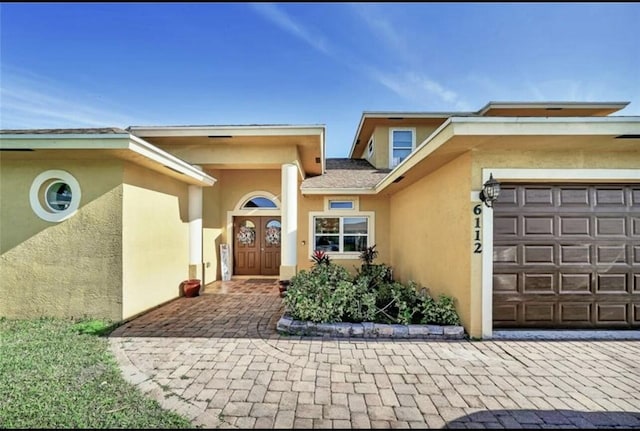 doorway to property with stucco siding and a garage