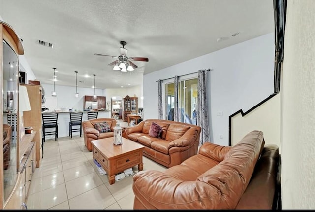 living room with light tile patterned floors, visible vents, and a ceiling fan