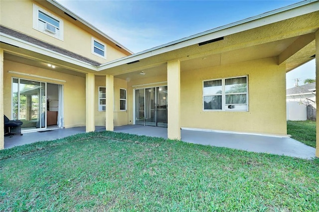 rear view of property with stucco siding, a yard, and a patio