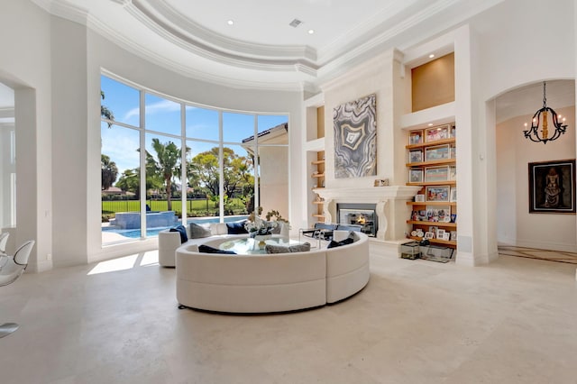 7090 Ayrshire Ln, Boca Raton, FL 33496 - living room featuring ornamental molding, built in shelves, a chandelier, a glass covered fireplace, and a high ceiling