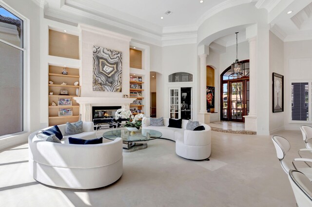 7090 Ayrshire Ln, Boca Raton, FL 33496 - living room with built in shelves, arched walkways, a glass covered fireplace, recessed lighting, and decorative columns