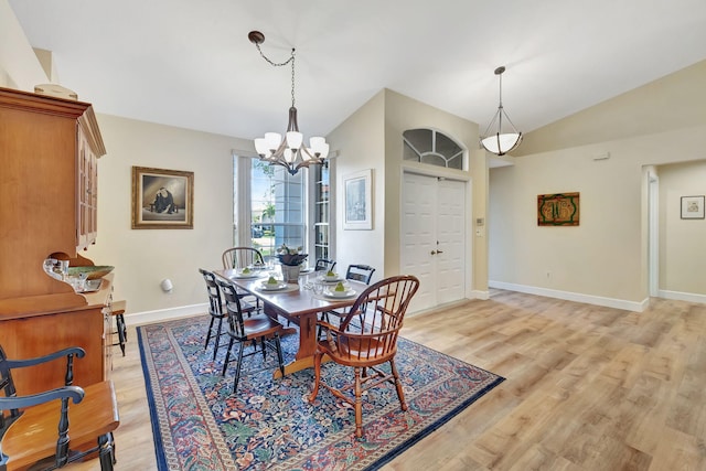 dining area featuring an inviting chandelier, light wood-type flooring, vaulted ceiling, and baseboards