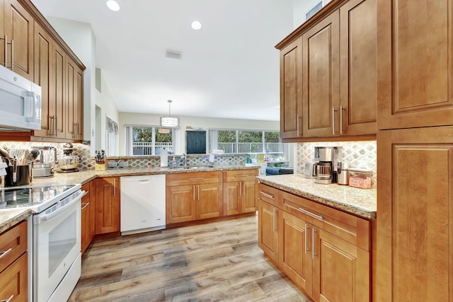 kitchen featuring tasteful backsplash, light stone countertops, white appliances, light wood finished floors, and visible vents