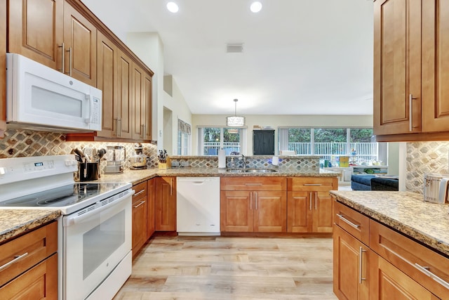 kitchen featuring tasteful backsplash, white appliances, light wood-style floors, and a sink