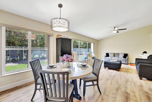 dining space with ceiling fan, baseboards, vaulted ceiling, and light wood-type flooring