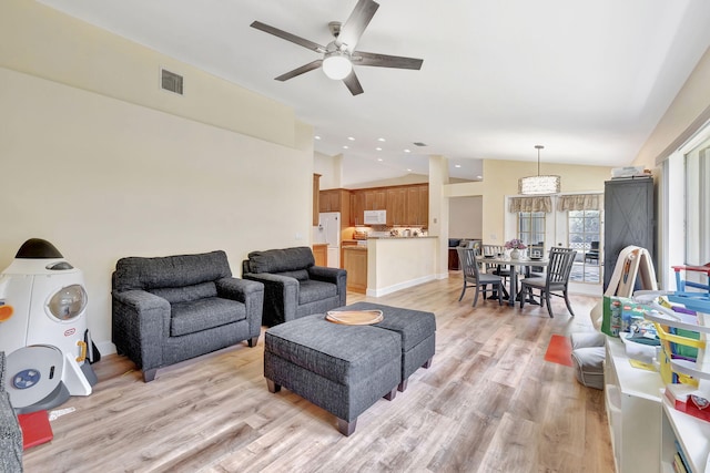 living room with lofted ceiling, visible vents, light wood-type flooring, and a ceiling fan